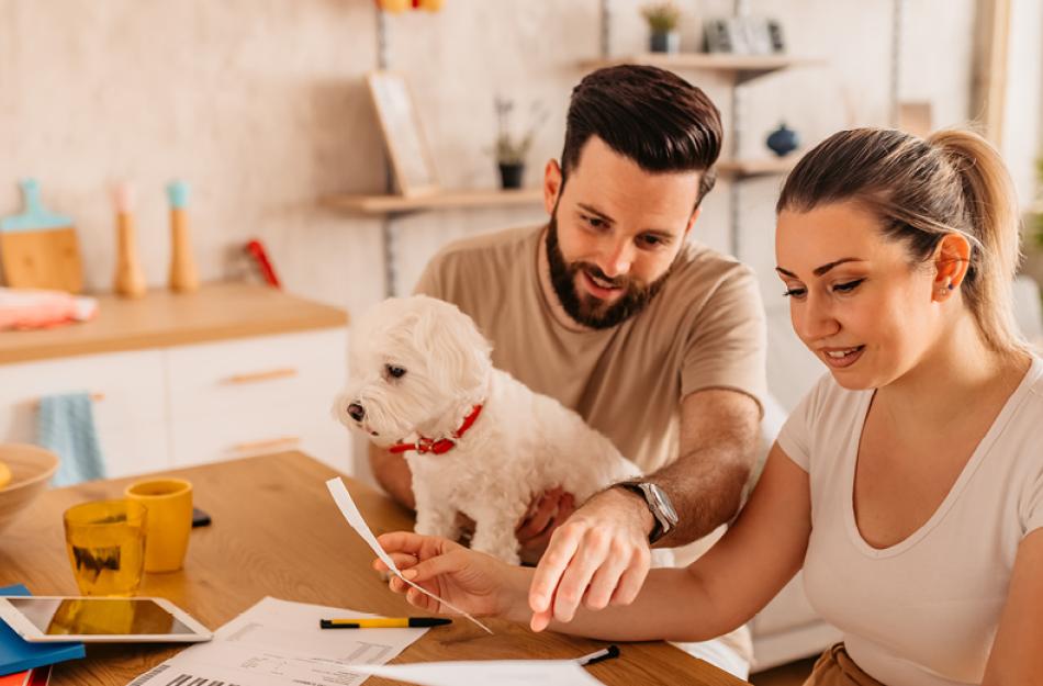 A guy and girl reviewing their bills in the kitchen.