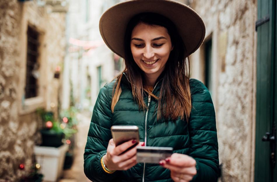 woman looking at her credit card and smartphone